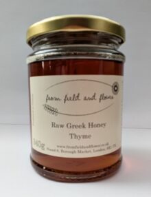 Jar of thyme honey sitting on a white background